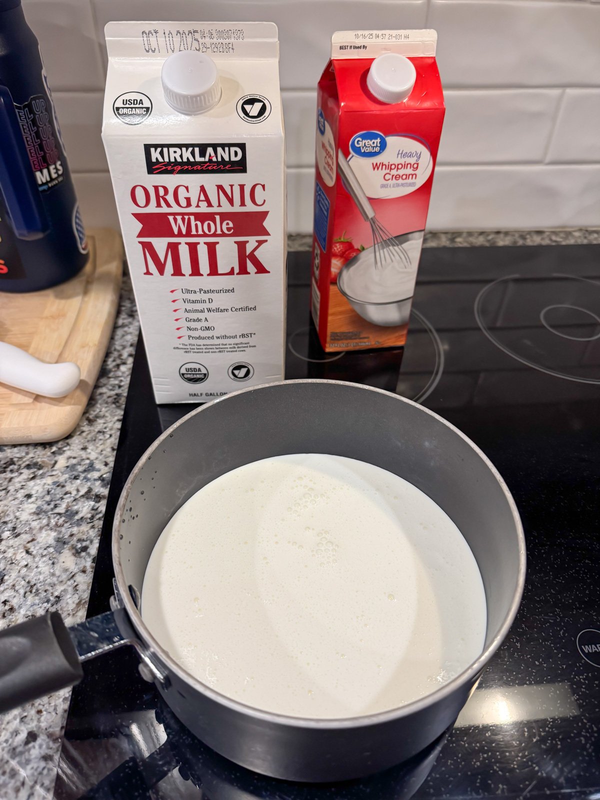 bringing whole milk and cream up to a boil in a pot on the stove.