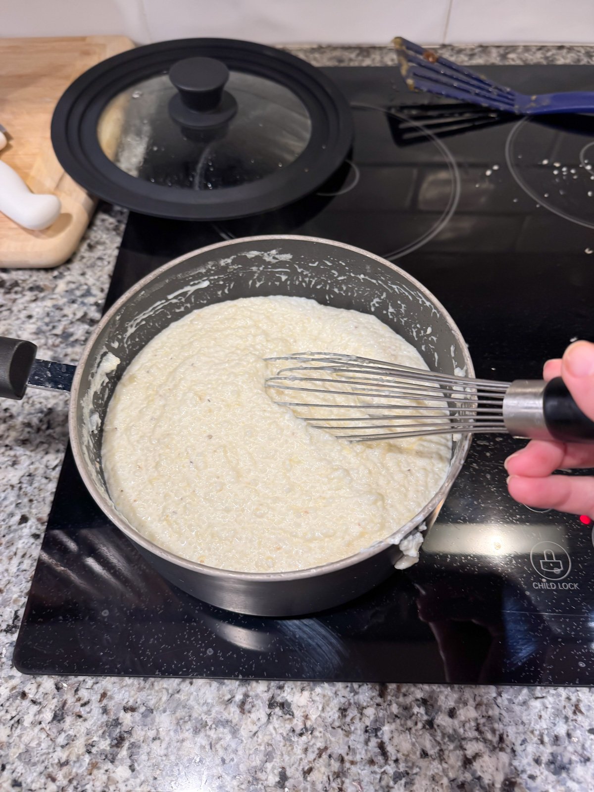 whisking cooked grits in a pot on the stove.