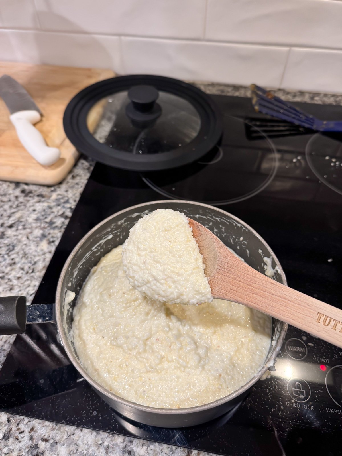 a wooden spoon scooping out some grits from a pot to show the desired thickness once cooked.