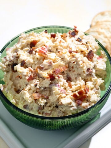 white cheddar pimento cheese in a green bowl with crackers next to it