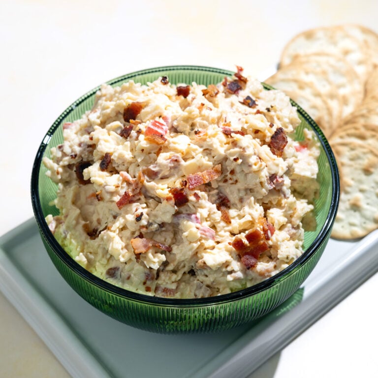 white cheddar pimento cheese in a green bowl with crackers next to it