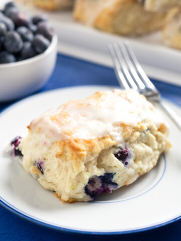 a small plate with a blueberry buttermilk biscuit and a fork on it.