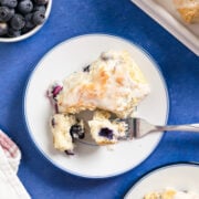 a small plate with a blueberry buttermilk biscuit on it with a fork that's taken a bite out of it