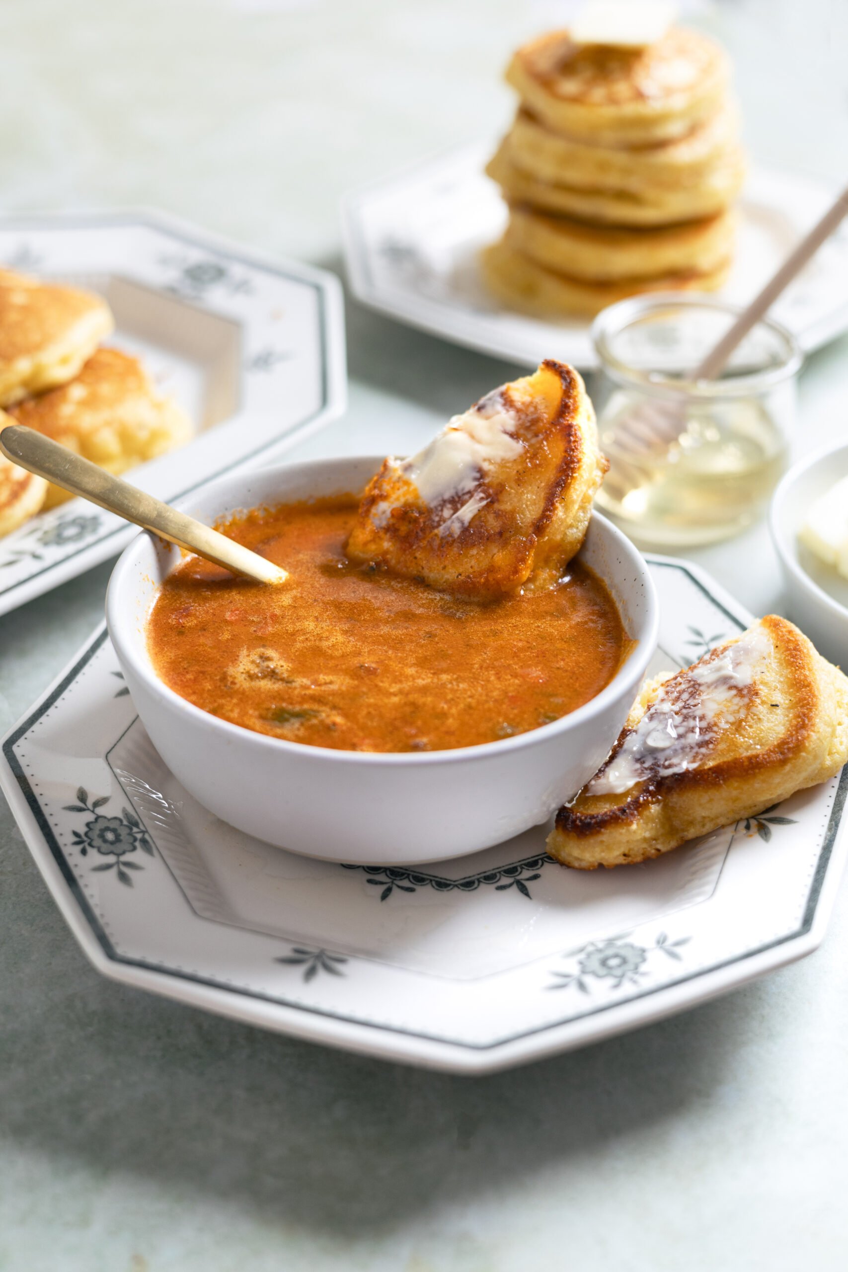 dipping in cornbread cakes in a bowl of chili.
