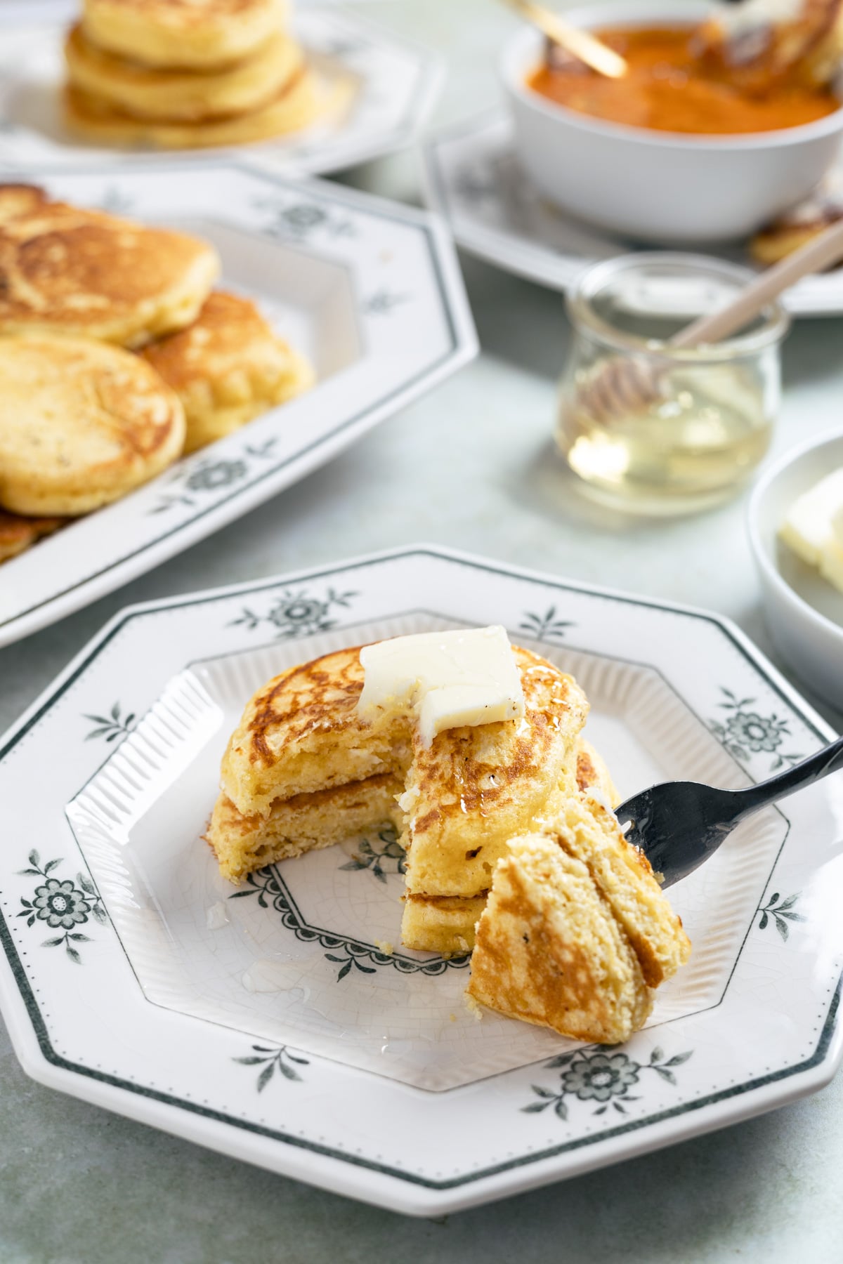 a fork cutting slices of fried cornbread with butter on top