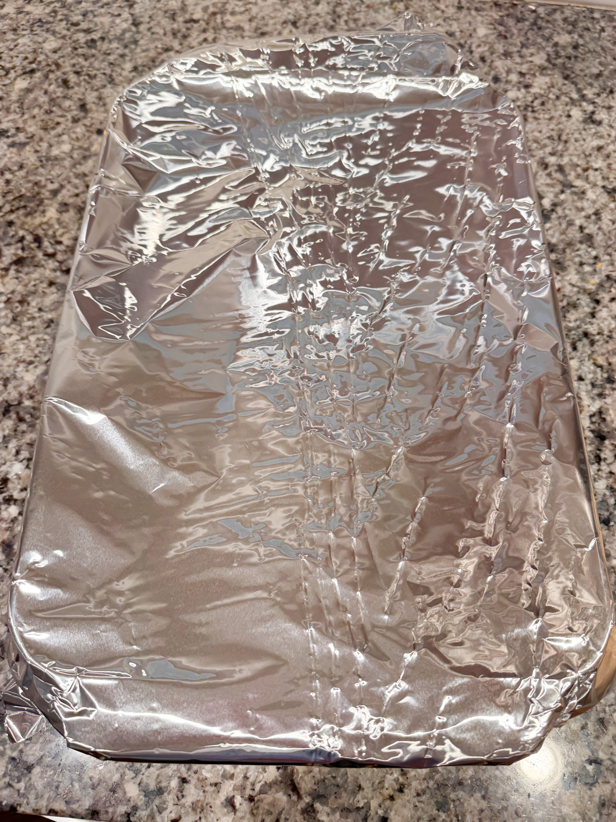 a baking dish wrapped in foil on a kitchen counter.