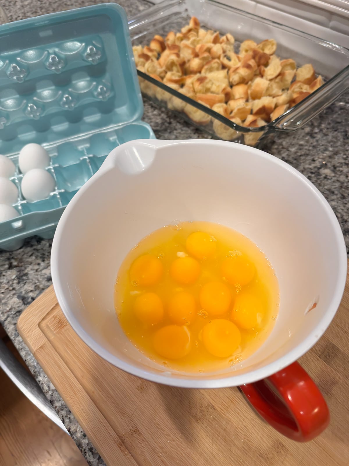 Adding eggs to a large mixing bowl.