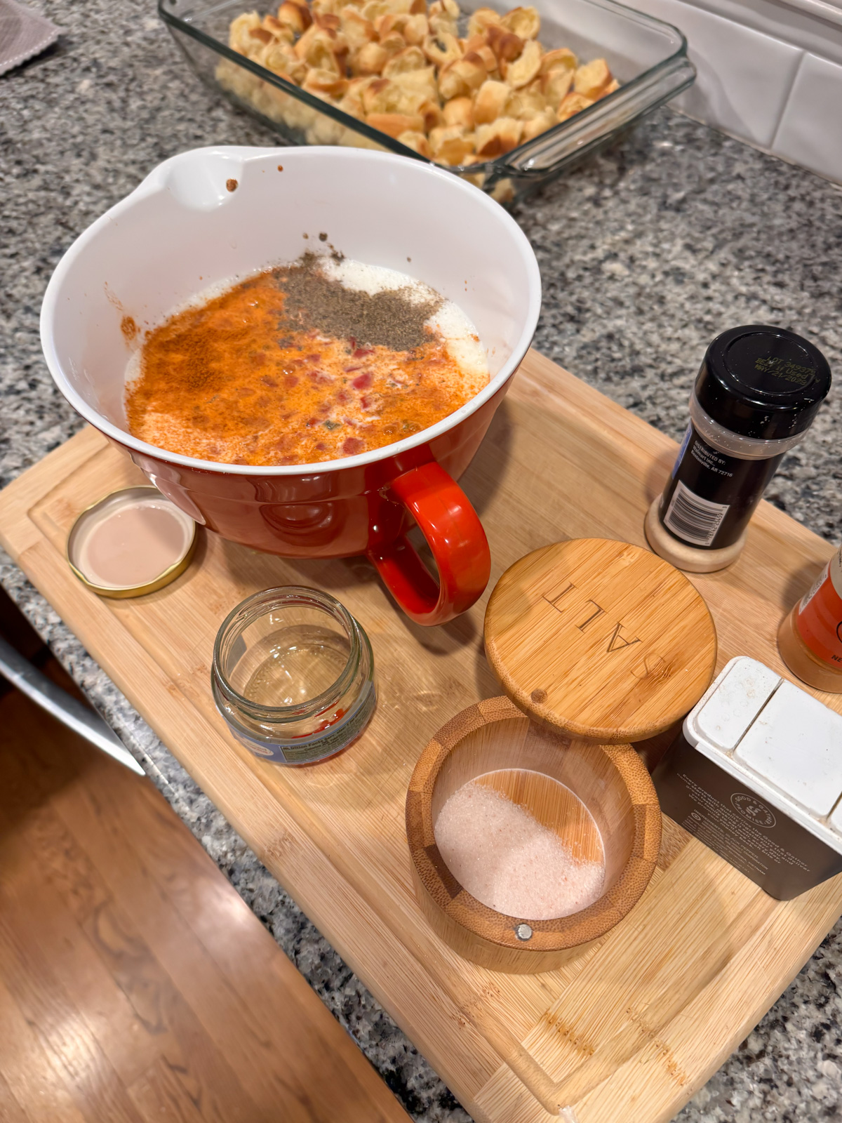 Adding milk, spices and pimentos to a large mixing bowl with eggs.