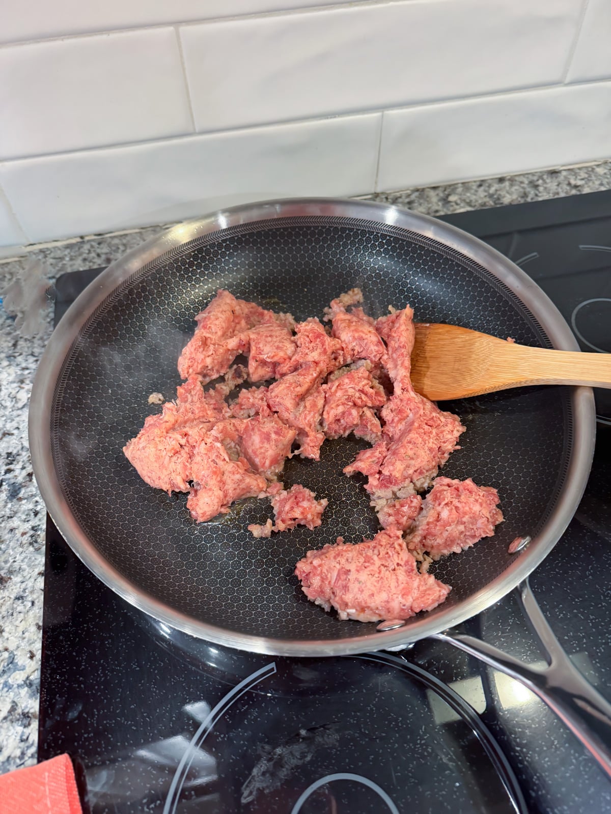 adding sausage to a large skillet on the stove