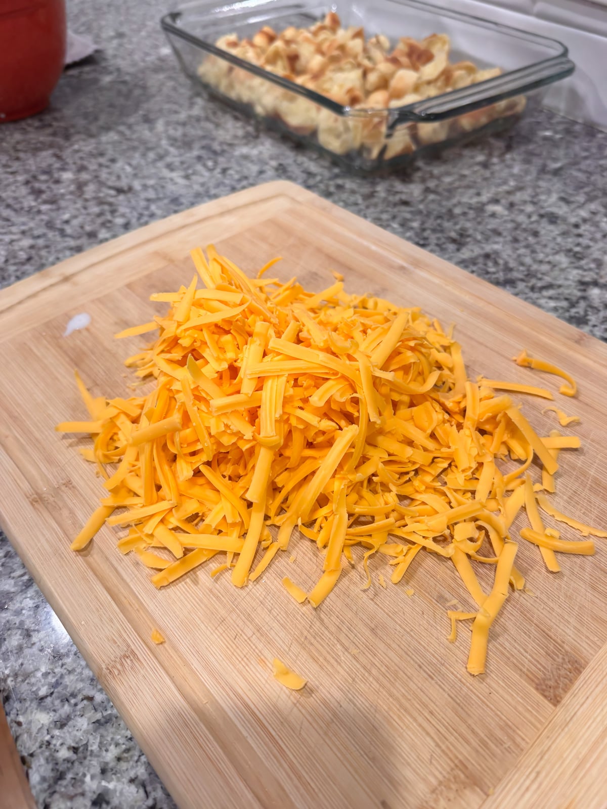 A pile of shredded cheese on a cutting board.