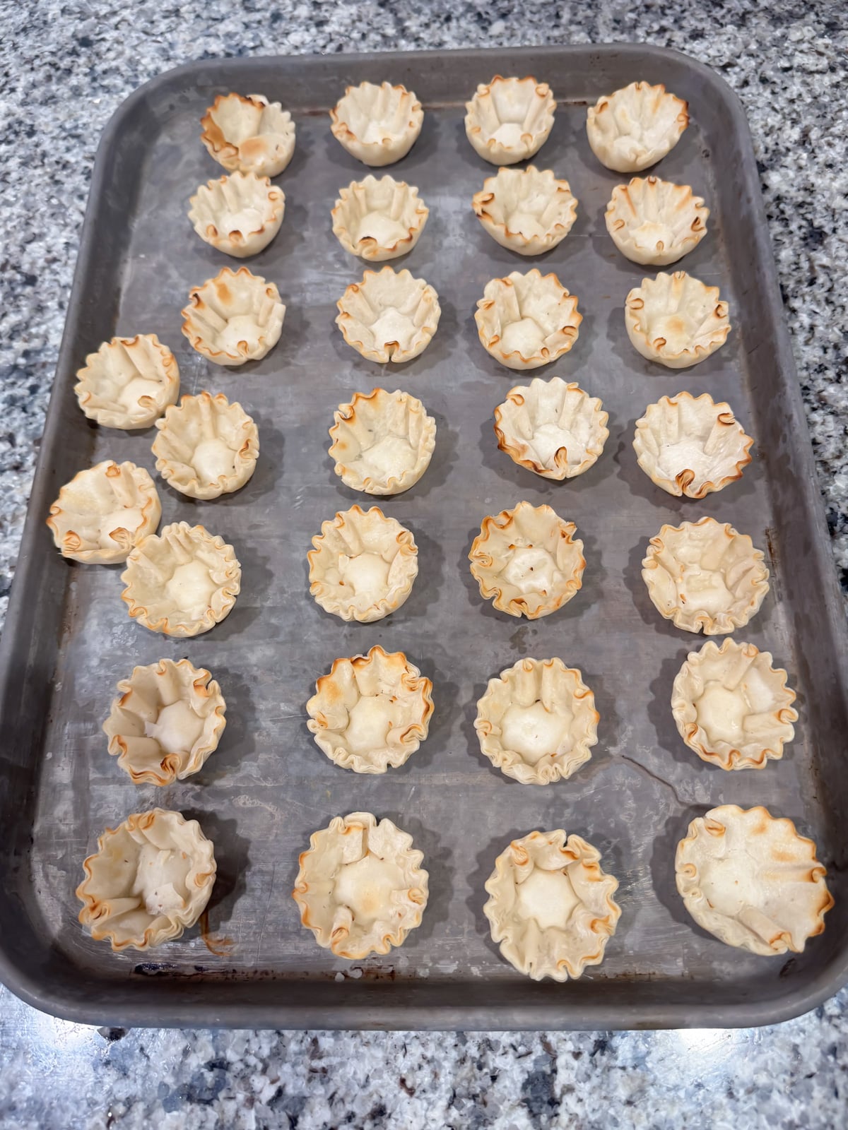 a baking tray with phyllo shells on it.