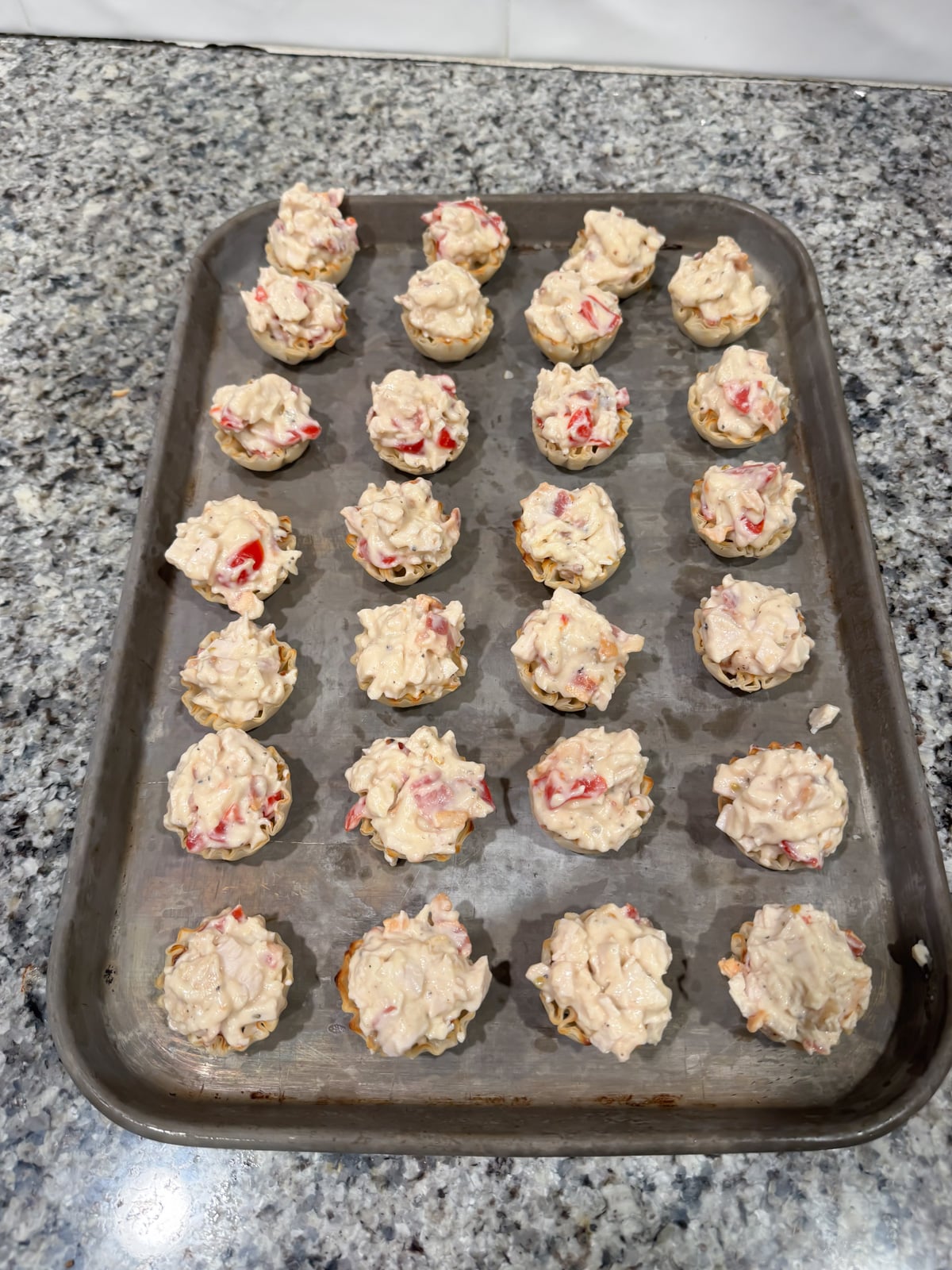 mini hot brown bites in phyllo shells on a baking try before going into the oven.