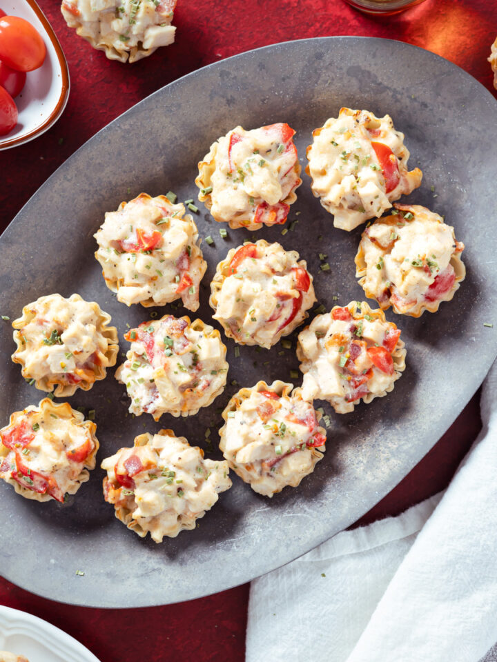 mini hot brown bites on a silver tray and a red background