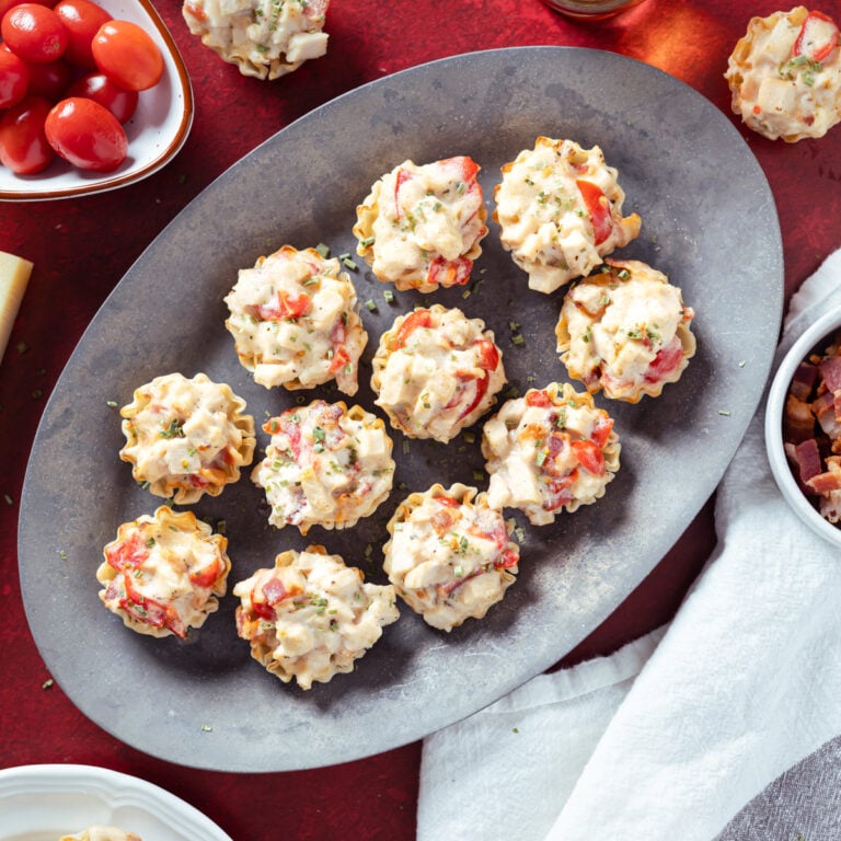 mini hot brown bites on a silver tray and a red background