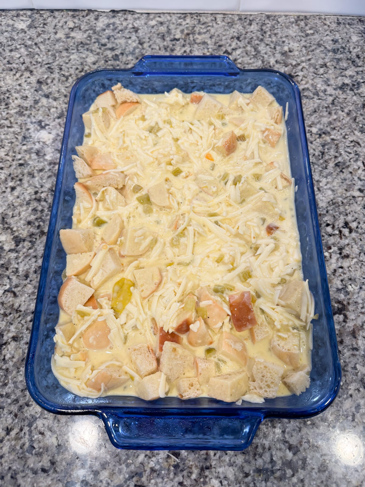 green chili egg breakfast casserole in a blue baking dish before going into the oven the oven to bake.