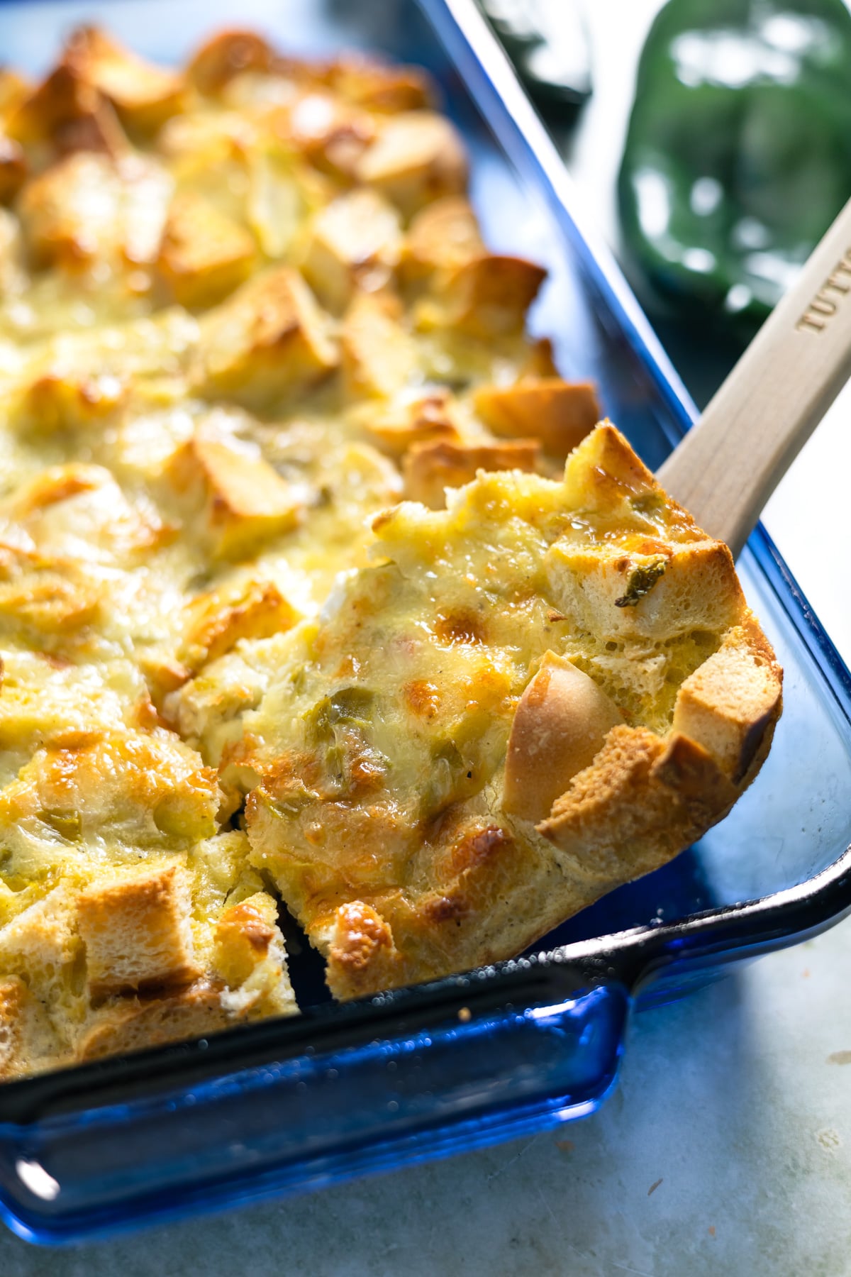 spooning out some green chili egg casserole from a baking dish