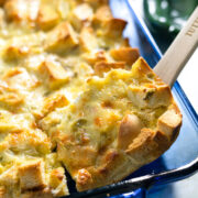 stopping our a serving of breakfast casserole with a wooden spoon from a baking dish.