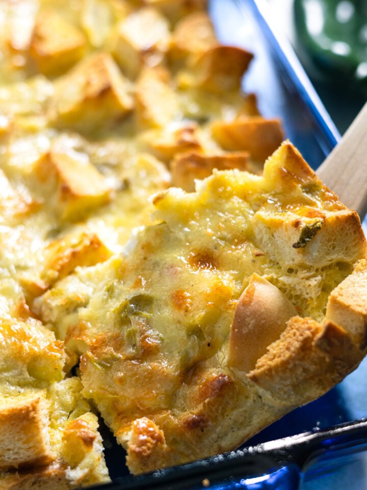 stopping our a serving of breakfast casserole with a wooden spoon from a baking dish.
