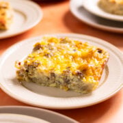 a slice of hash brown breakfast casserole on a small plate on an orange background
