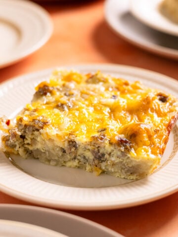 a slice of hash brown breakfast casserole on a small plate on an orange background