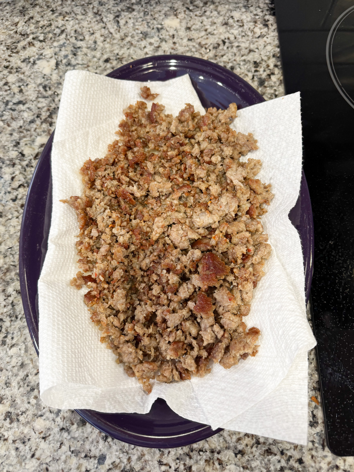 Cooling cooked sausage on a paper towel lined plate.