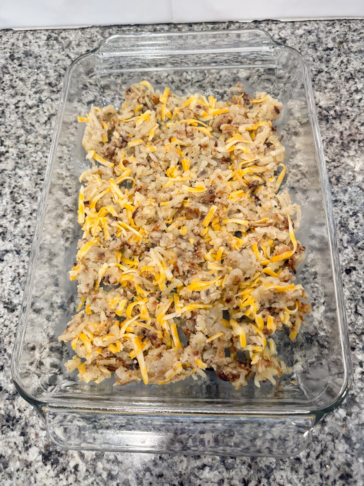 A layer of hash browns and cheese in a greased 9x13 baking dish.