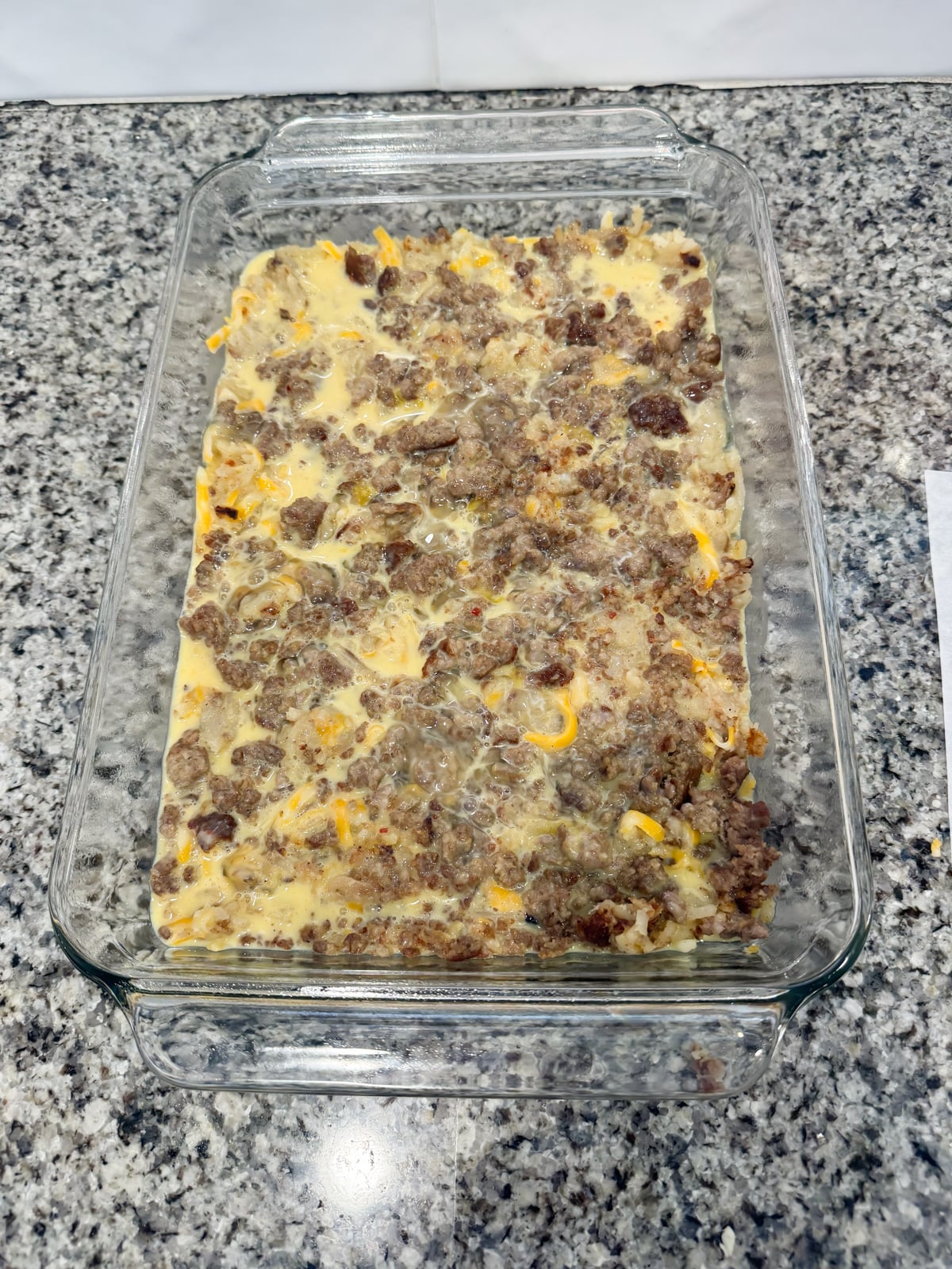Adding egg mixture to hash brown casserole baking pan.