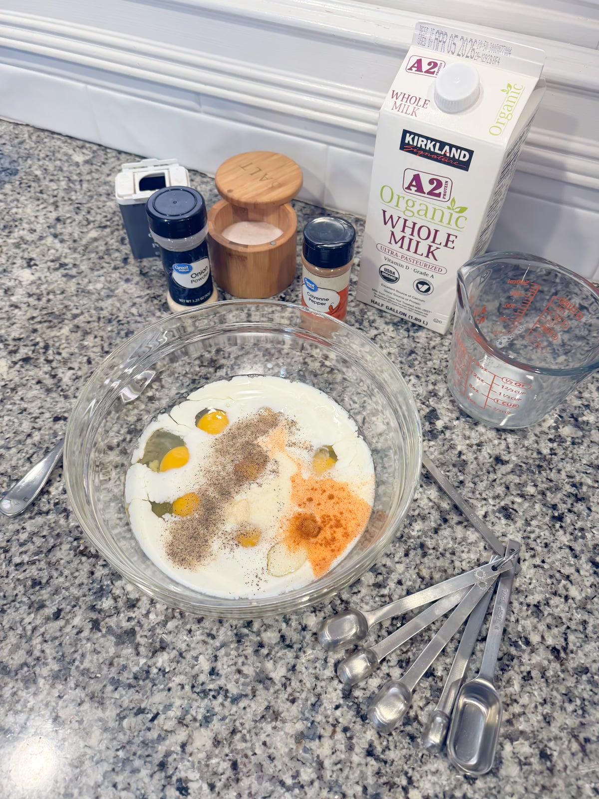 eggs, milk, and spices in a large bowl on the kitchen counter.